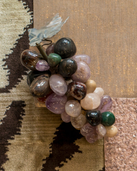 A small bunch of grapes in various semi-precious stones with a metal leaf.